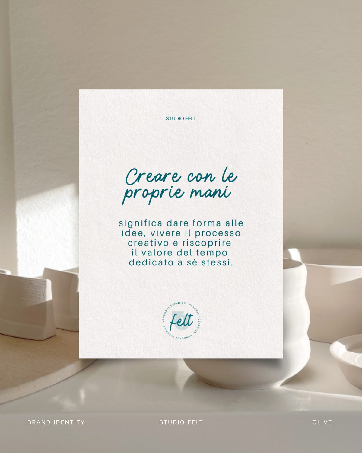 Cartolina con la frase «Creare con le proprie mani» appoggiata su una mensola con ceramiche